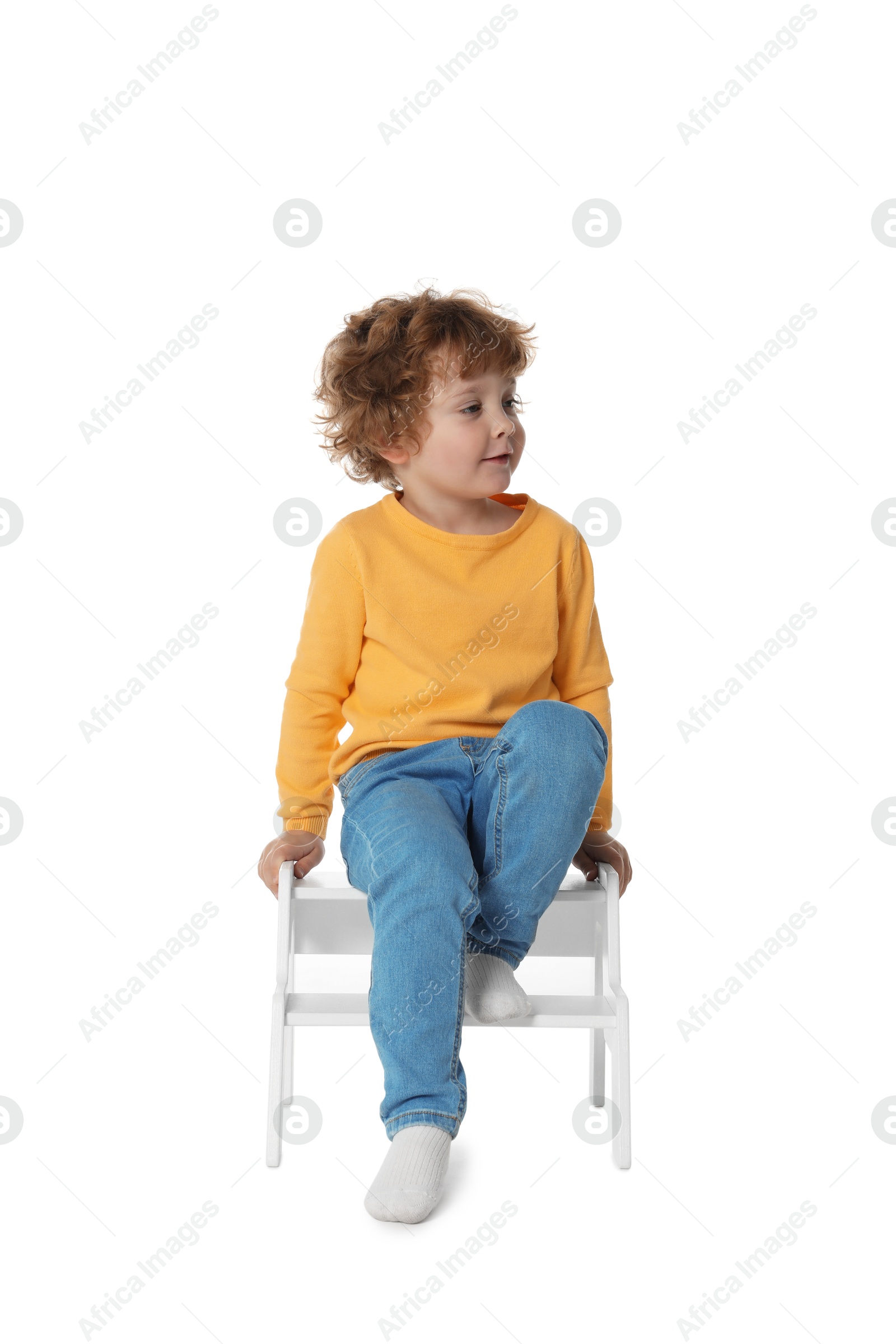 Photo of Little boy sitting on step stool against white background