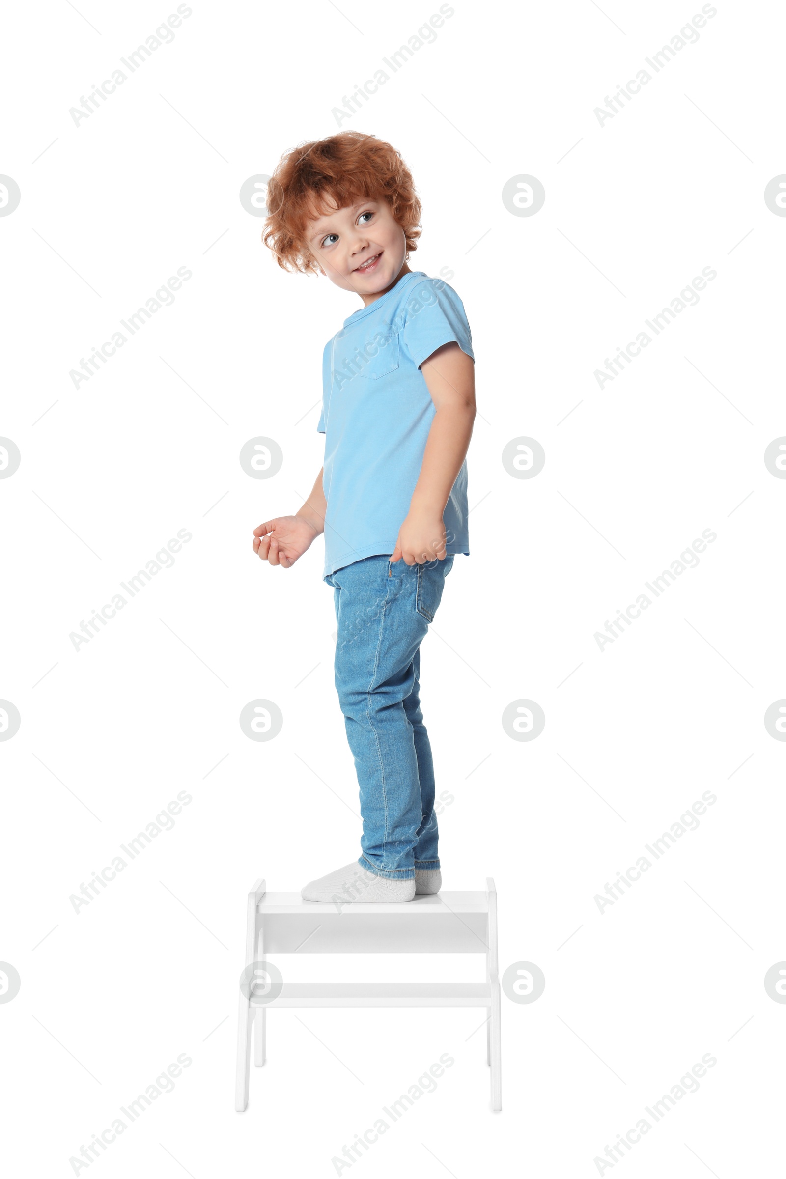 Photo of Little boy standing on step stool against white background