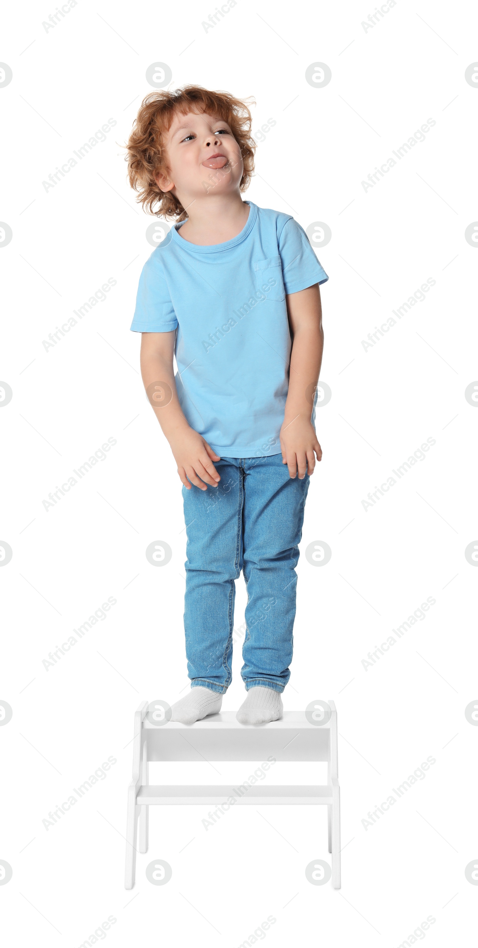 Photo of Little boy standing on step stool against white background