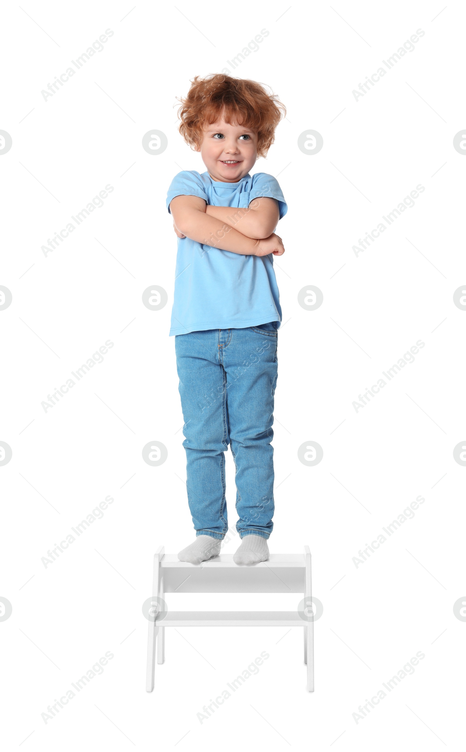 Photo of Little boy standing on step stool against white background