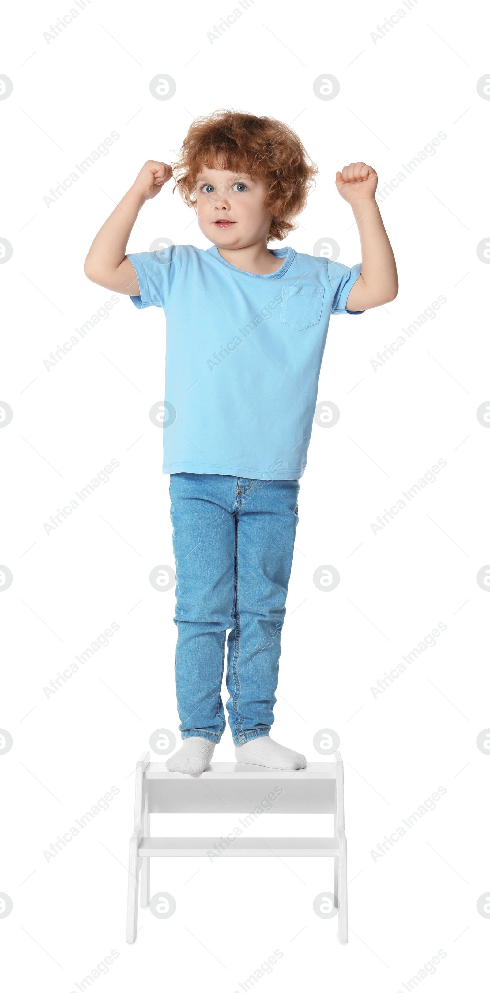 Photo of Little boy standing on step stool against white background