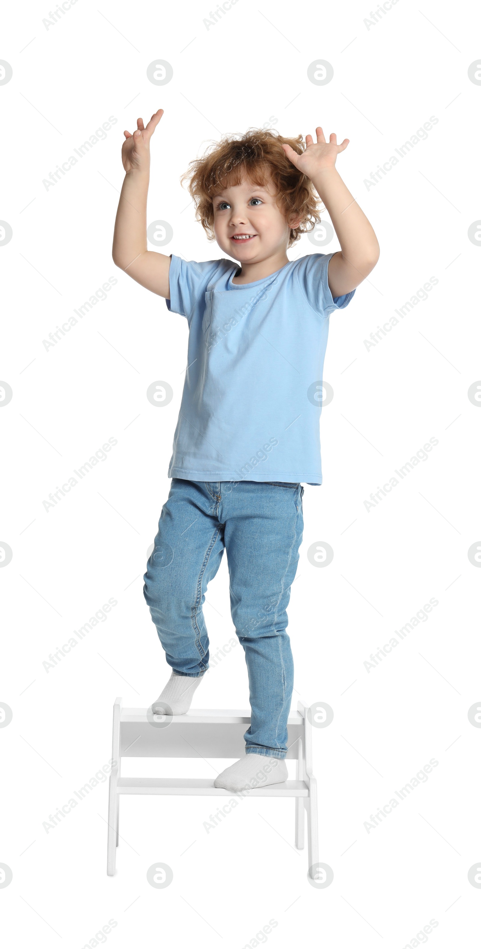 Photo of Little boy standing on step stool against white background