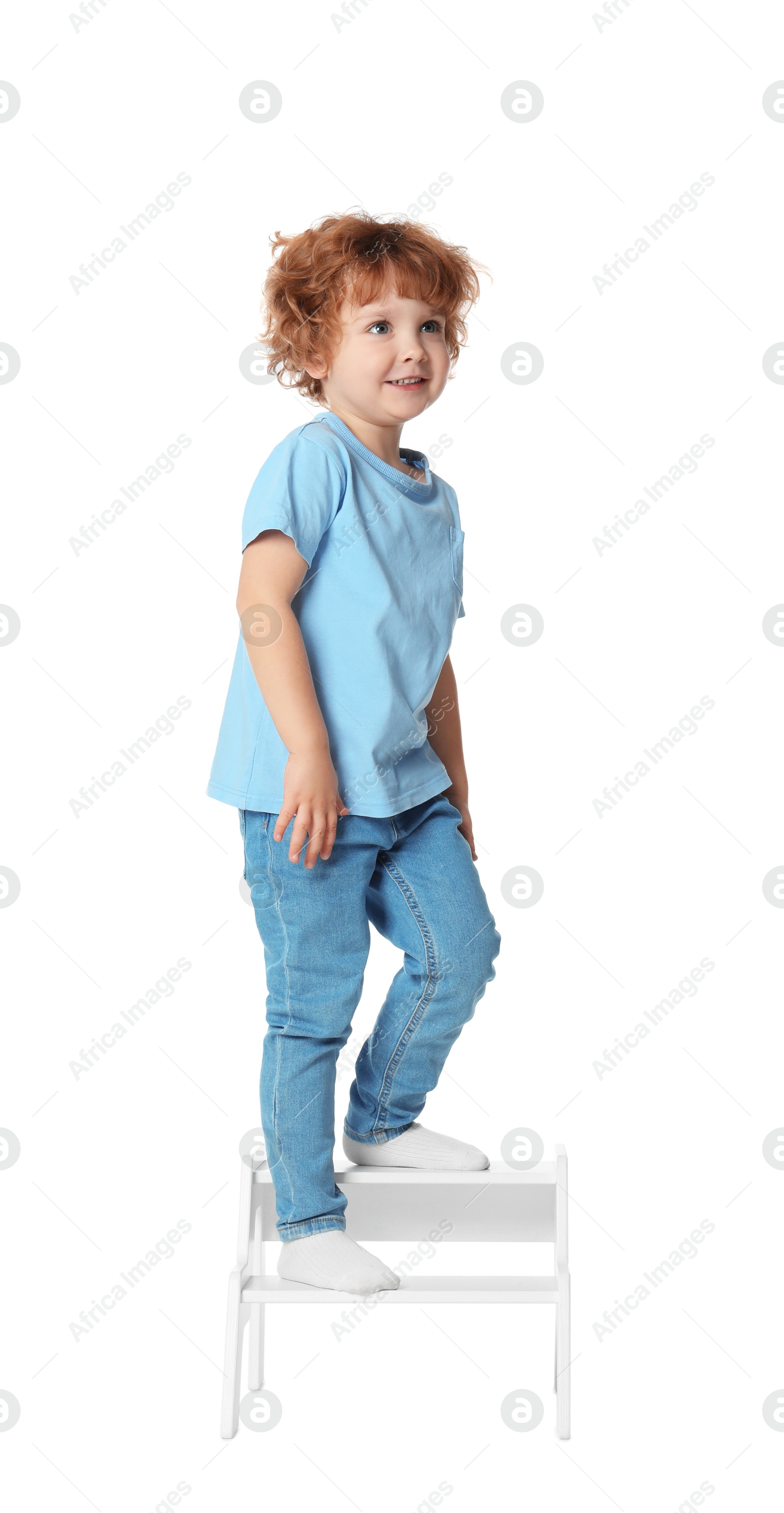 Photo of Little boy standing on step stool against white background