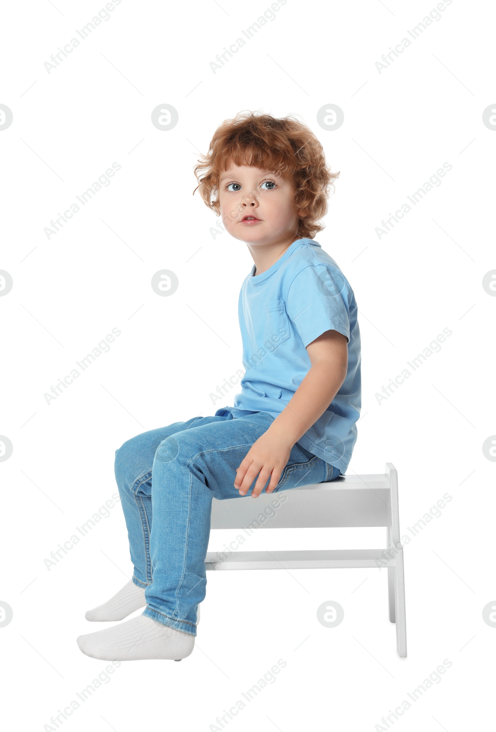 Photo of Little boy sitting on step stool against white background