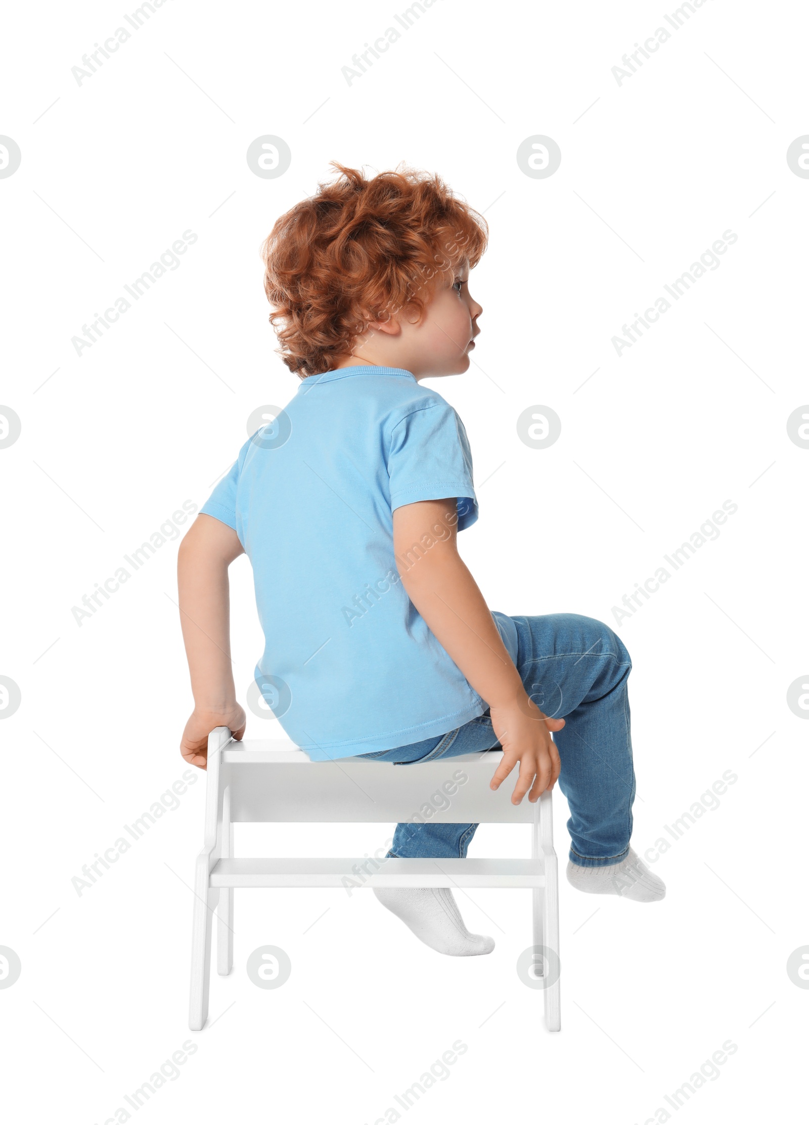 Photo of Little boy sitting on step stool against white background