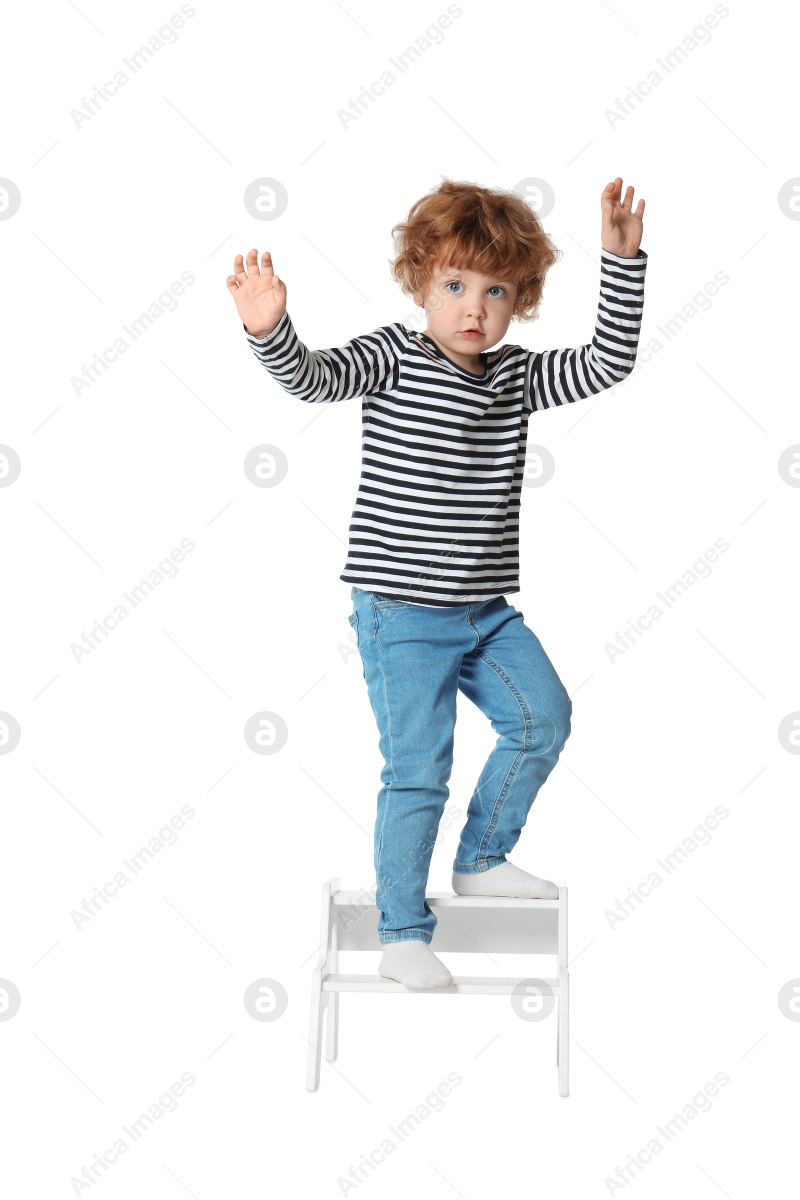 Photo of Little boy standing on step stool against white background