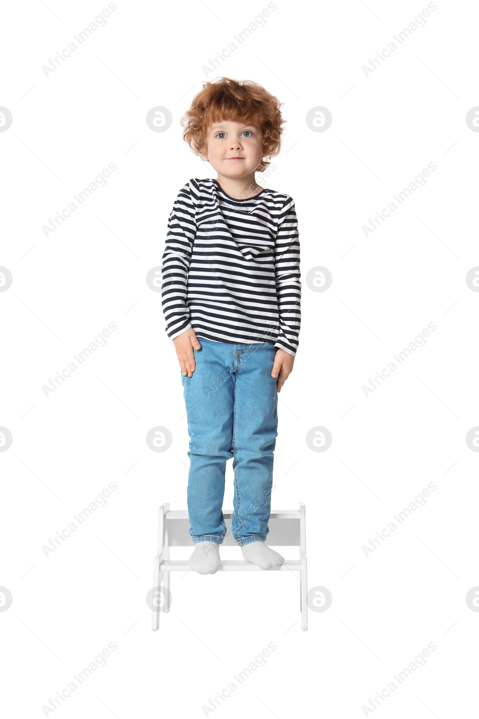 Photo of Little boy standing on step stool against white background