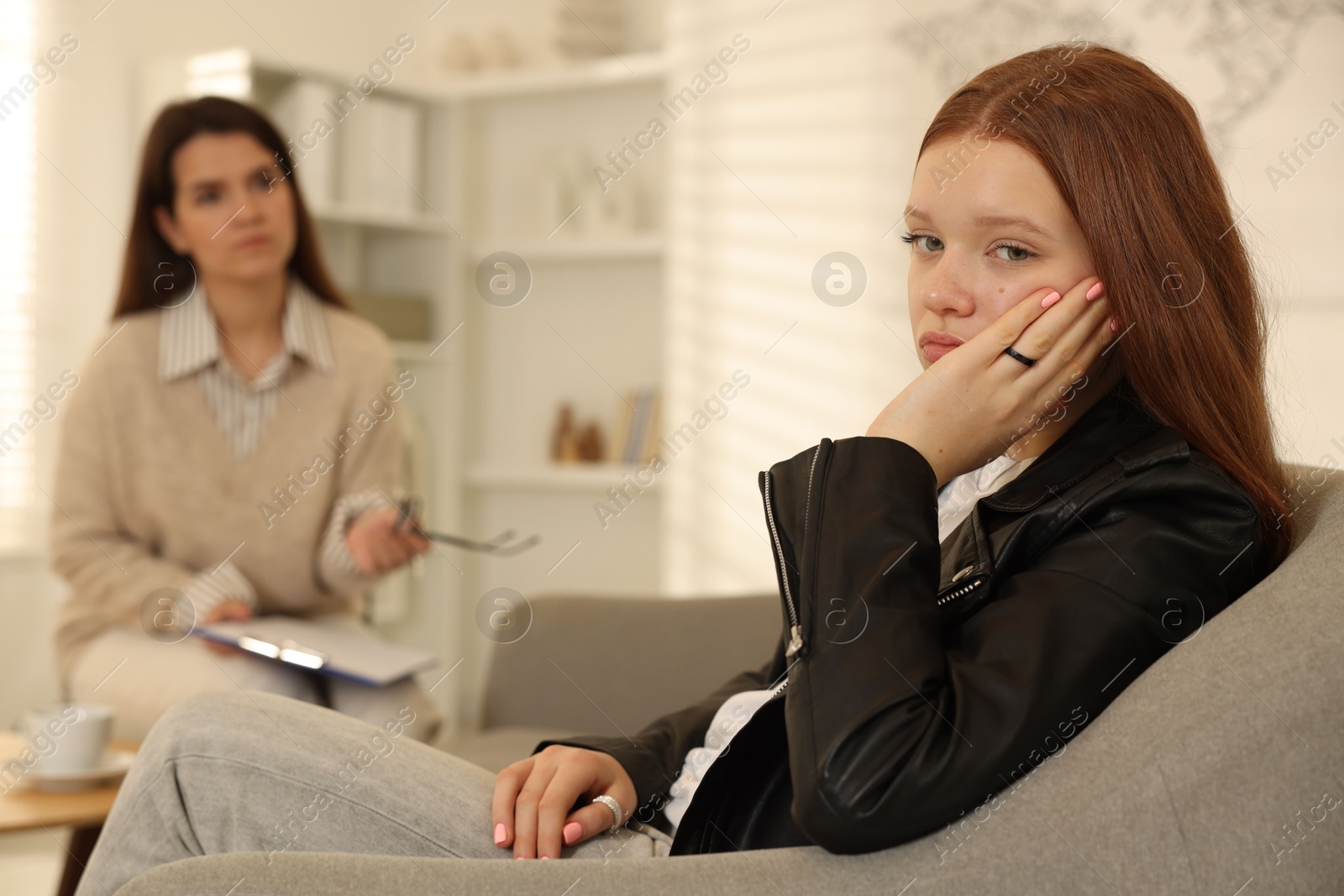 Photo of Psychologist working with difficult teenage girl in office, selective focus