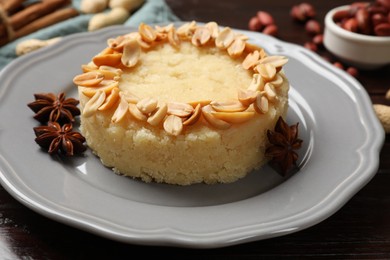 Photo of Delicious semolina halva with almond flakes and spices on wooden table, closeup