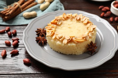 Photo of Delicious semolina halva with almond flakes and spices on wooden table, closeup