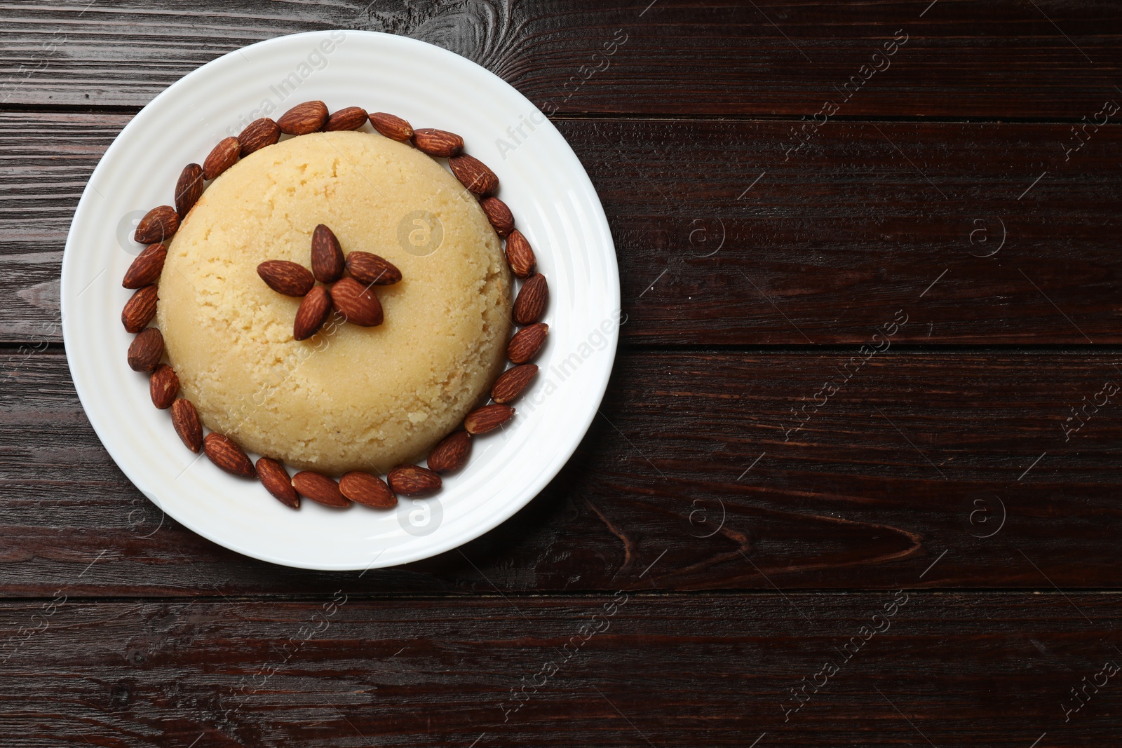 Photo of Delicious semolina halva with almonds on wooden table, top view. Space for text