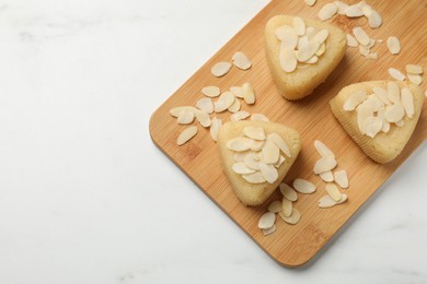 Photo of Pieces of delicious semolina halva with almond flakes on white table, top view. Space for text