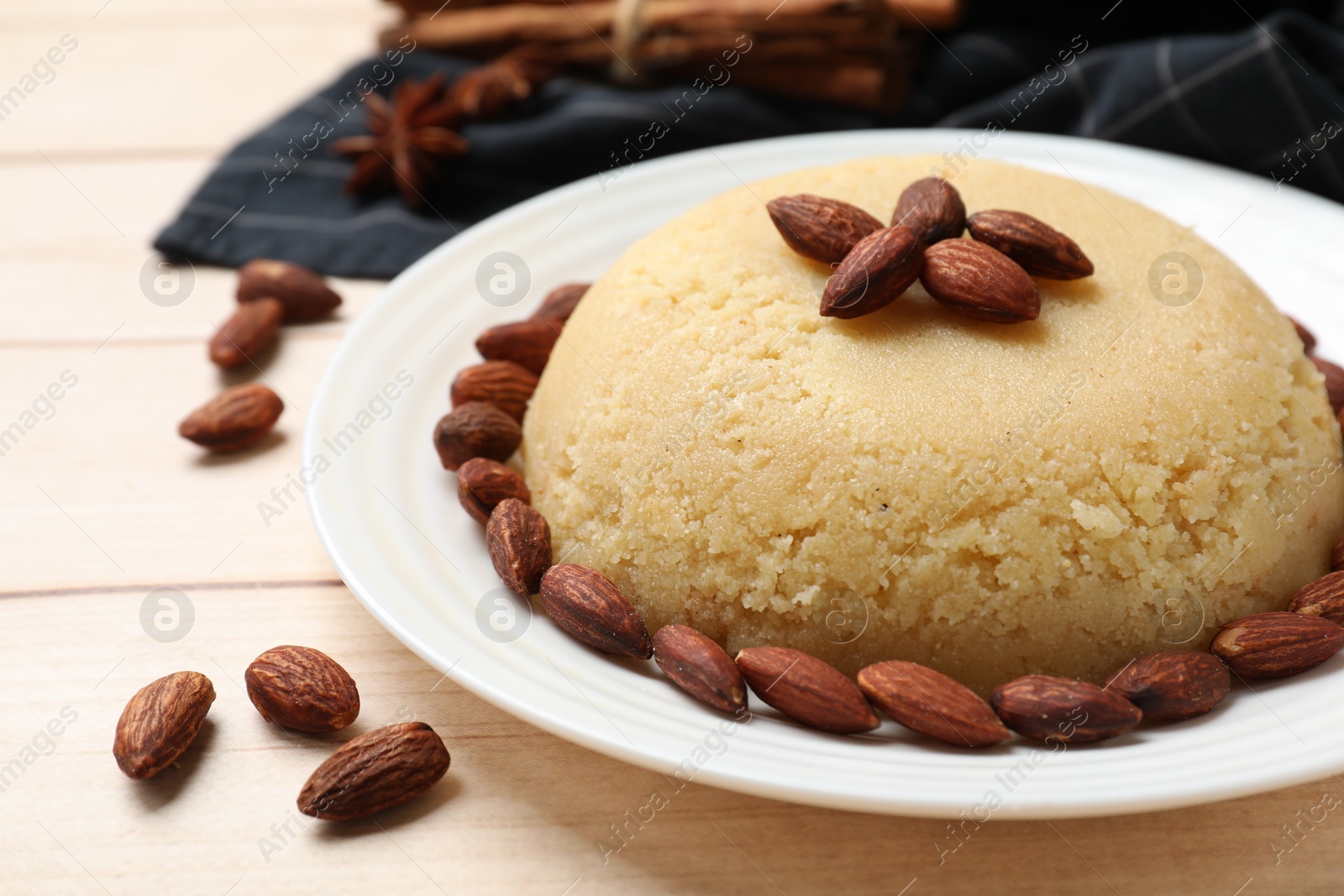 Photo of Delicious semolina halva with almonds on white wooden table, closeup