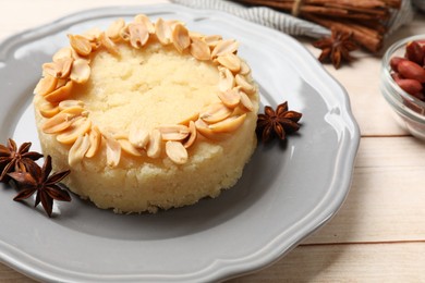 Photo of Delicious semolina halva with almond flakes and spices on white wooden table, closeup