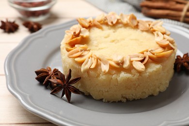 Photo of Delicious semolina halva with almond flakes and spices on white wooden table, closeup