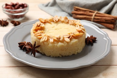 Photo of Delicious semolina halva with almond flakes and spices on white wooden table, closeup