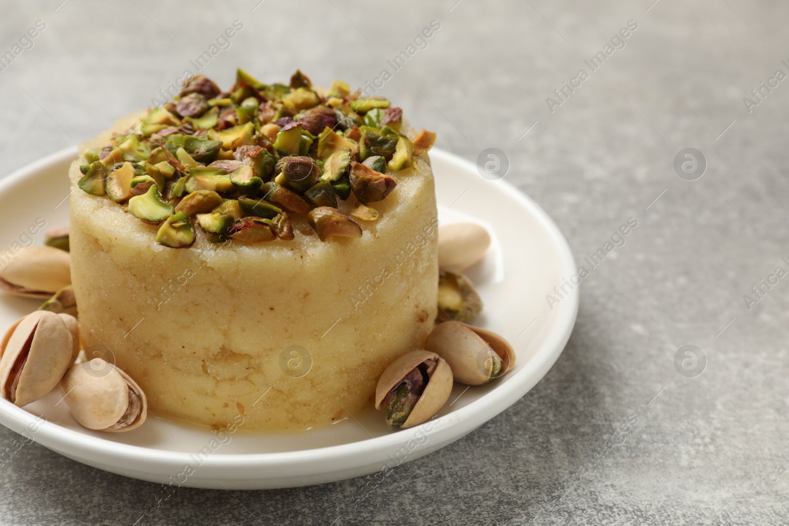 Photo of Delicious sweet semolina halva with pistachios on light grey table, closeup