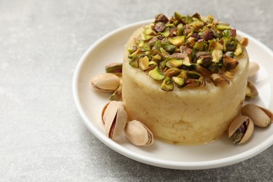 Photo of Delicious sweet semolina halva with pistachios on light grey table, closeup