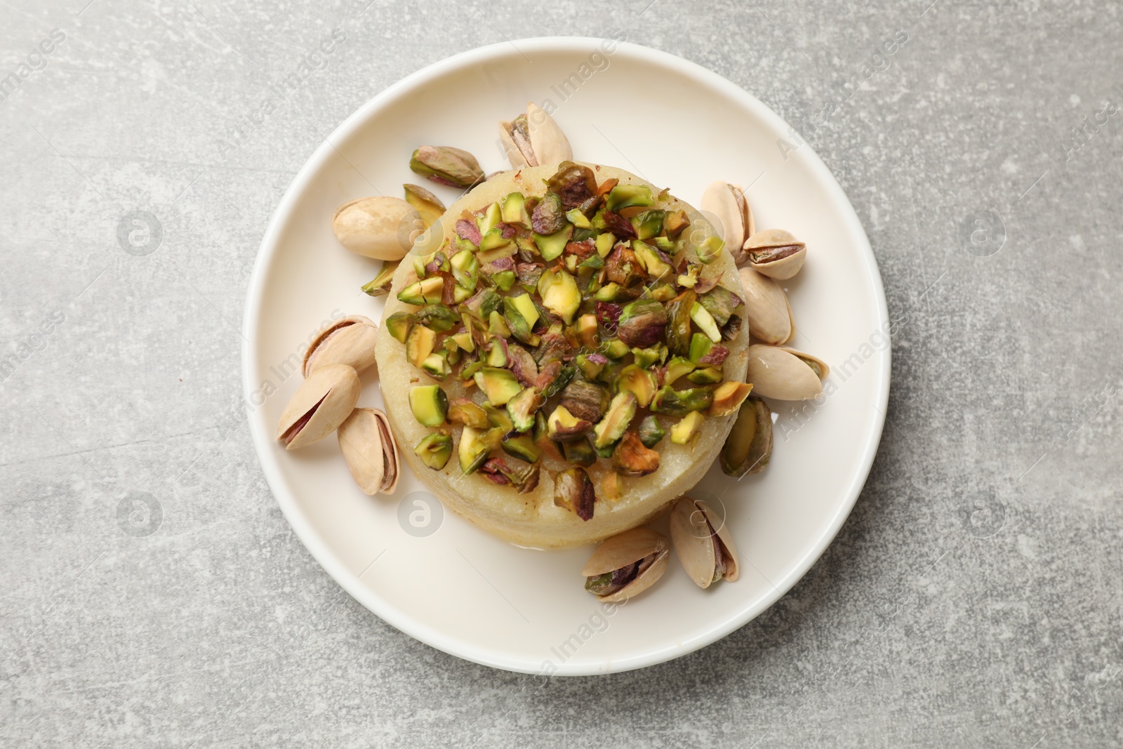 Photo of Delicious sweet semolina halva with pistachios on light grey table, top view