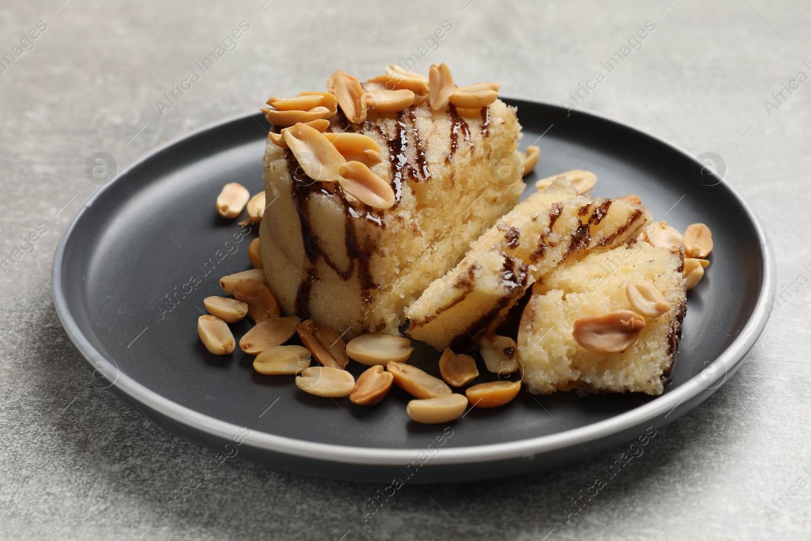 Photo of Delicious sweet semolina halva with peanuts on light grey table, closeup