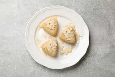 Photo of Pieces of delicious sweet semolina halva with almond flakes on light grey table, top view