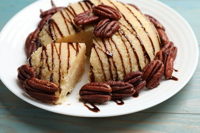 Photo of Delicious sweet semolina halva with pecans on blue wooden table, closeup