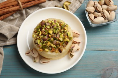 Photo of Delicious sweet semolina halva with pistachios on blue wooden table, flat lay