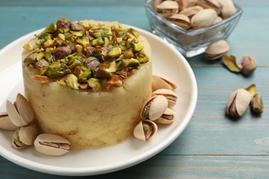 Photo of Delicious sweet semolina halva with pistachios on blue wooden table, closeup