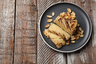 Photo of Delicious sweet semolina halva with peanuts on wooden table, top view. Space for text