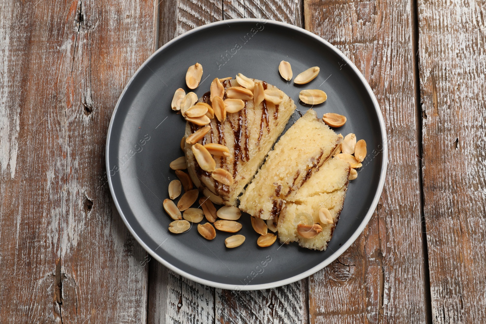 Photo of Delicious sweet semolina halva with peanuts on wooden table, top view