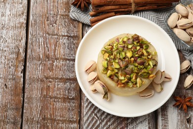 Photo of Delicious sweet semolina halva with pistachios and spices on wooden table, flat lay. Space for text