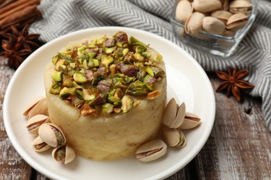 Photo of Delicious sweet semolina halva with pistachios and spices on wooden table, closeup