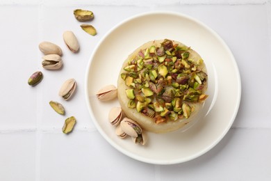 Photo of Delicious sweet semolina halva with pistachios on white tiled table, top view