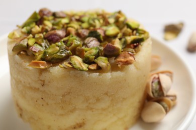 Photo of Delicious sweet semolina halva with pistachios on white table, closeup