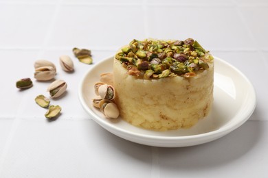 Photo of Delicious sweet semolina halva with pistachios on white tiled table