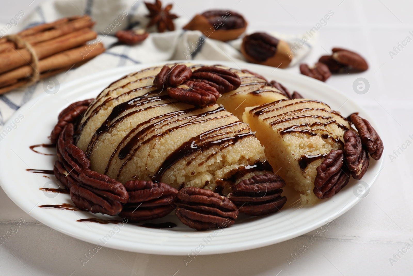 Photo of Delicious sweet semolina halva with pecans on white tiled table, closeup