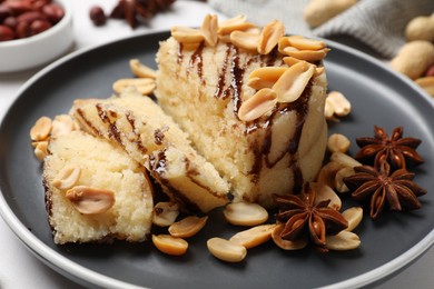 Photo of Delicious sweet semolina halva with peanuts and spices on white table, closeup