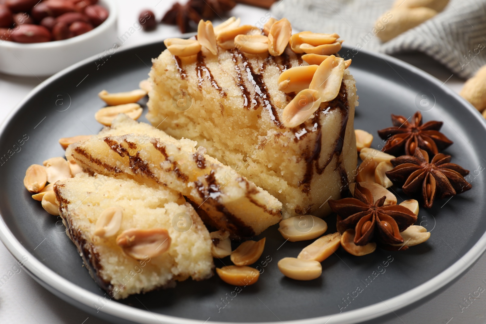 Photo of Delicious sweet semolina halva with peanuts and spices on white table, closeup