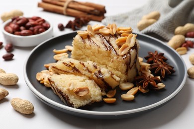 Photo of Delicious sweet semolina halva with peanuts and spices on white table, closeup