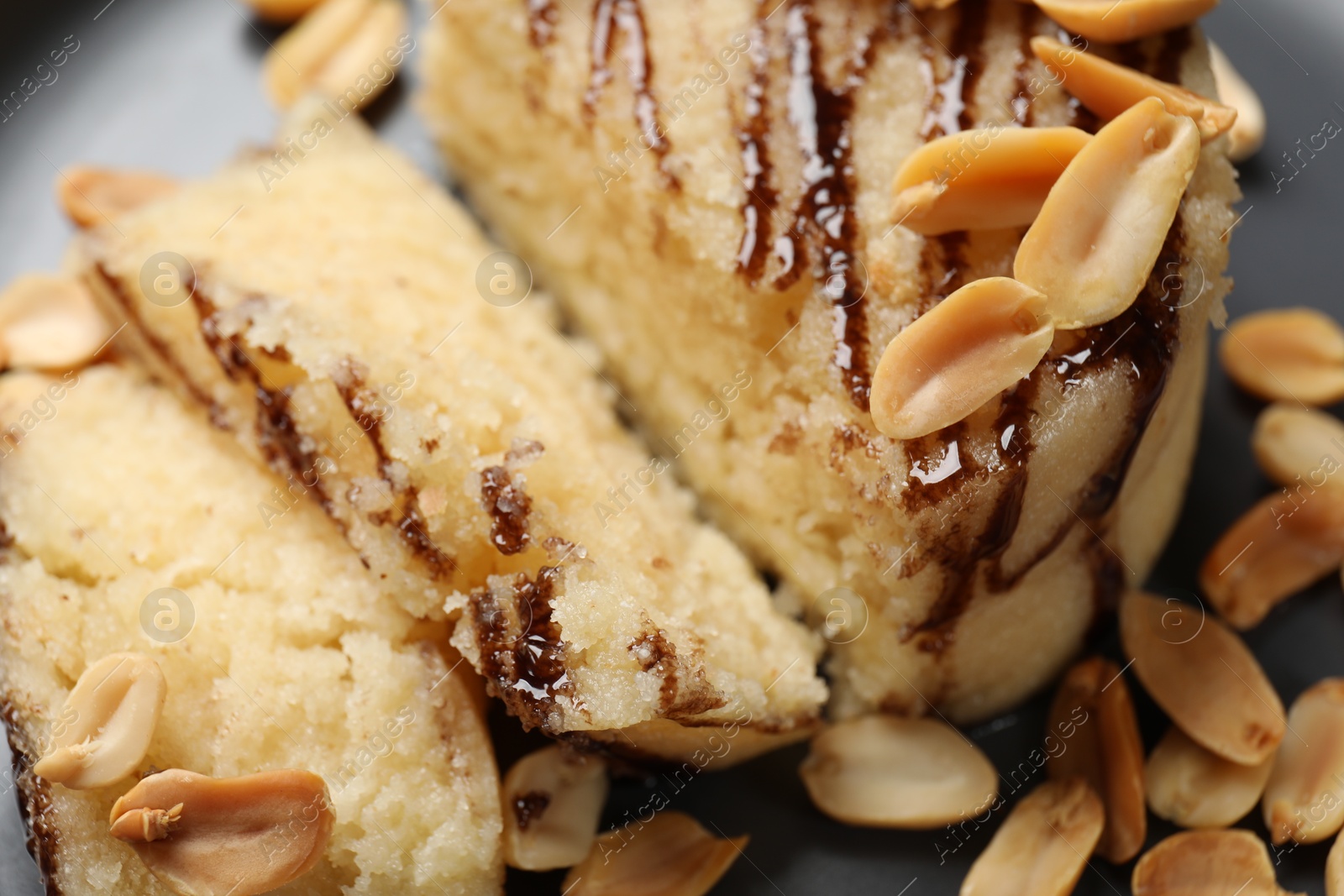 Photo of Delicious sweet semolina halva with peanuts on plate, closeup