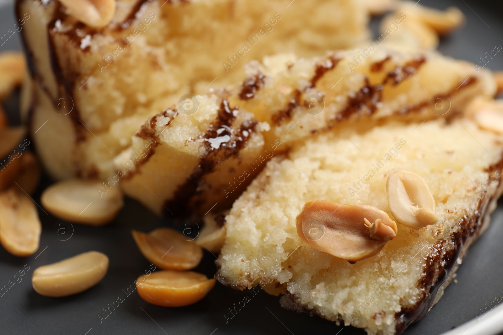 Photo of Delicious sweet semolina halva with peanuts on plate, closeup