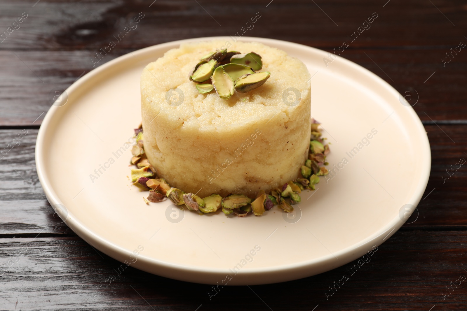 Photo of Delicious sweet semolina halva with pistachios on wooden table, closeup