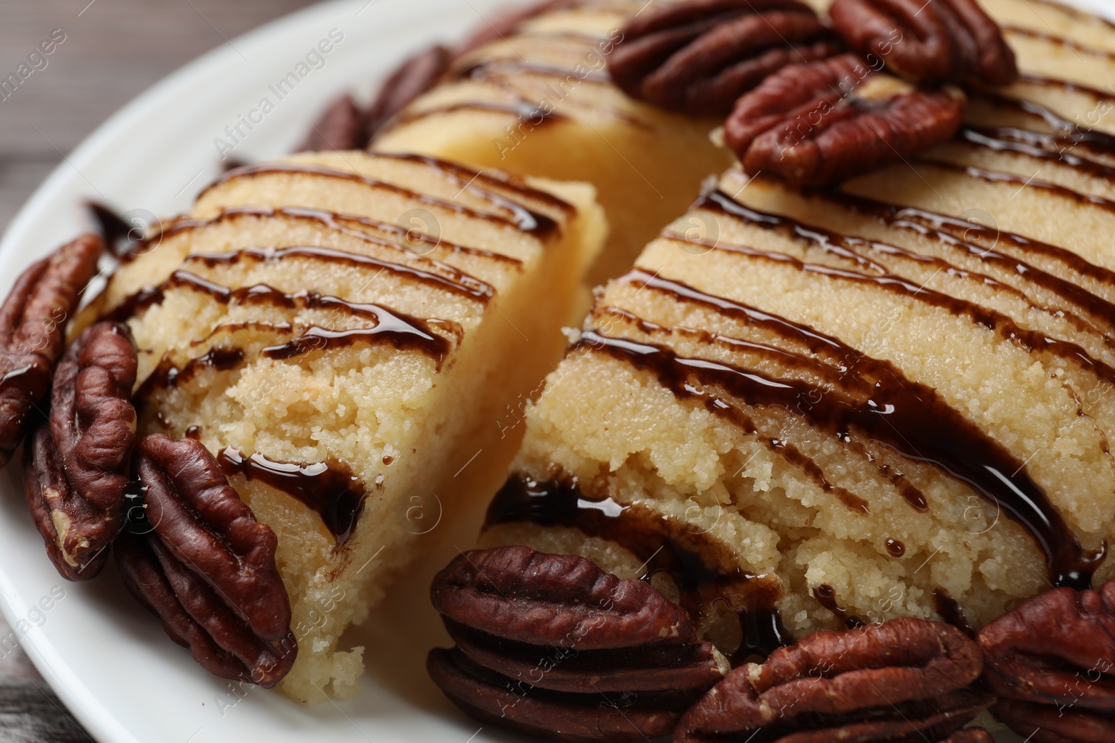 Photo of Delicious sweet semolina halva with pecans on table, closeup