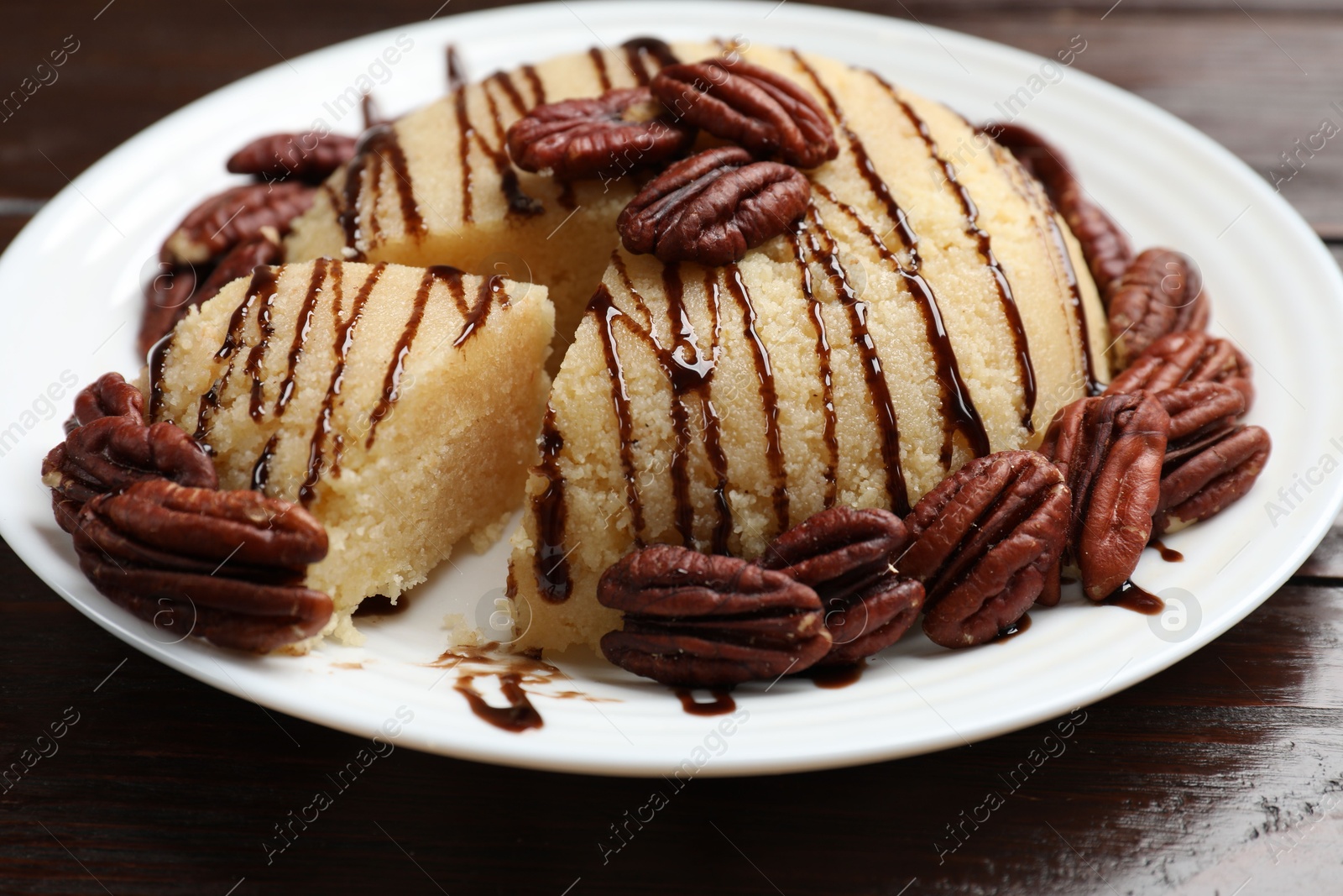 Photo of Delicious sweet semolina halva with pecans on wooden table, closeup