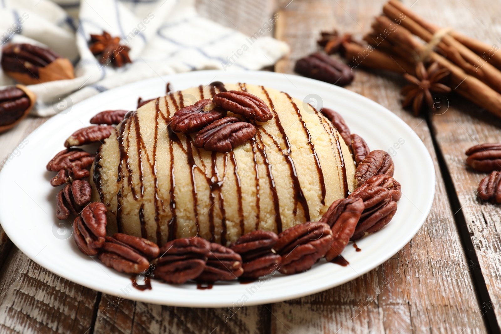 Photo of Delicious sweet semolina halva with pecans and spices on wooden table, closeup