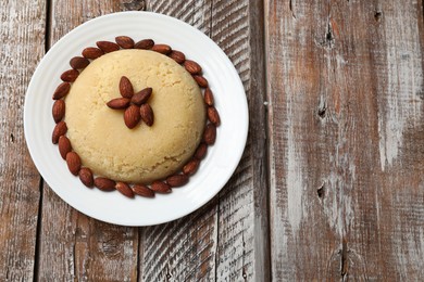 Photo of Delicious sweet semolina halva with almond on wooden table, top view. Space for text