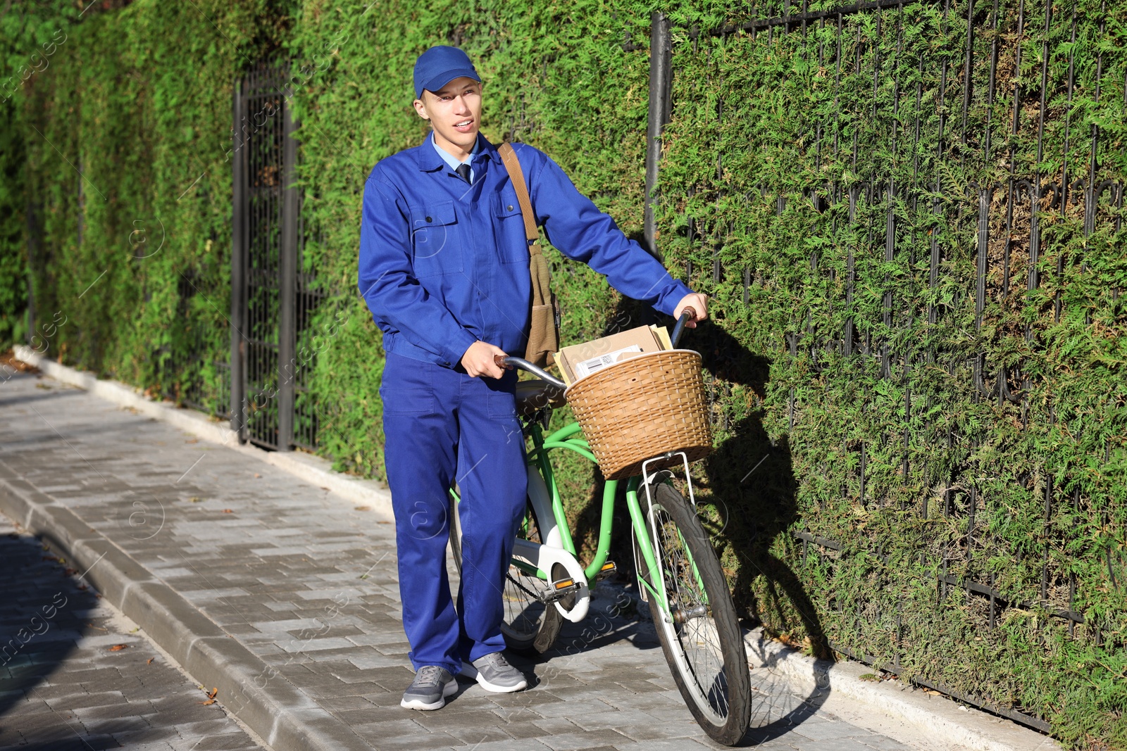 Photo of Postman with parcels in bicycle basket outdoors