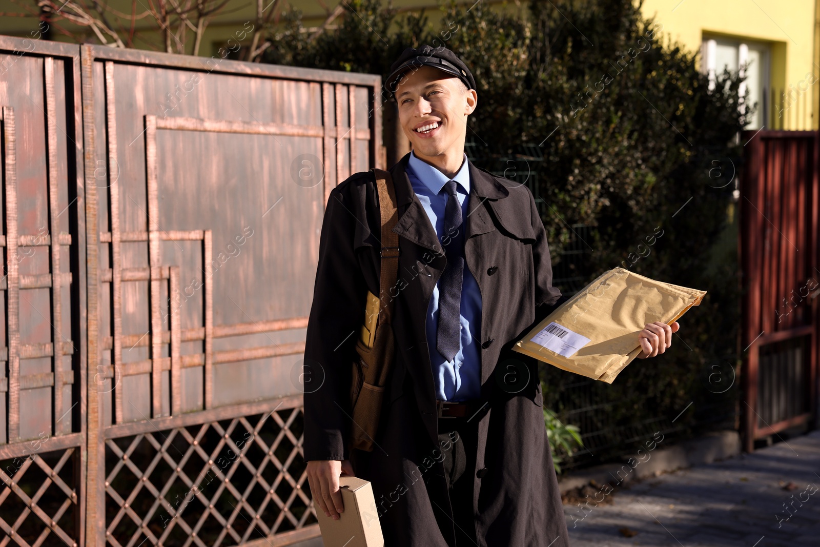 Photo of Happy postman with parcels outdoors. Mail service