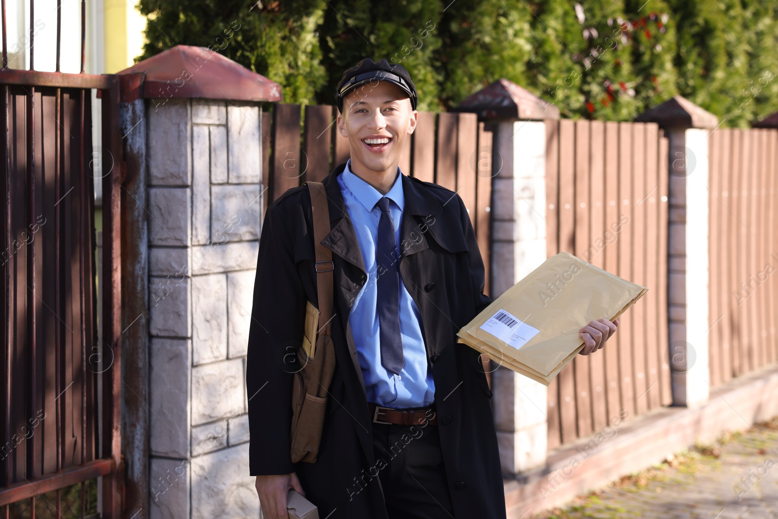 Photo of Happy postman with parcels outdoors. Mail service