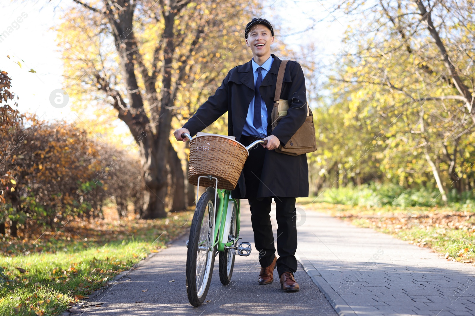 Photo of Happy mailman with bicycle outdoors. Postal service